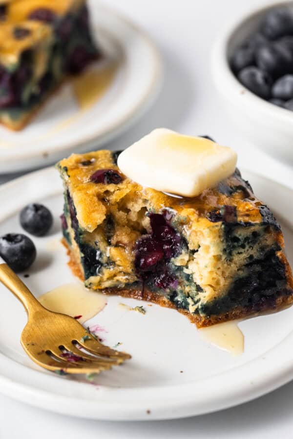 Blueberry breakfast cake on a plate with a gold fork.