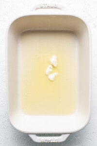 Butter in a baking dish on a white surface.