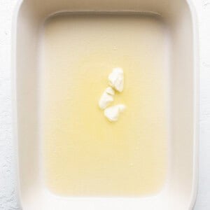 Butter in a baking dish on a white surface.