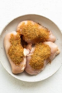 Seasoned chicken breasts on a white plate.