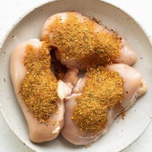 Seasoned chicken breasts on a white plate.