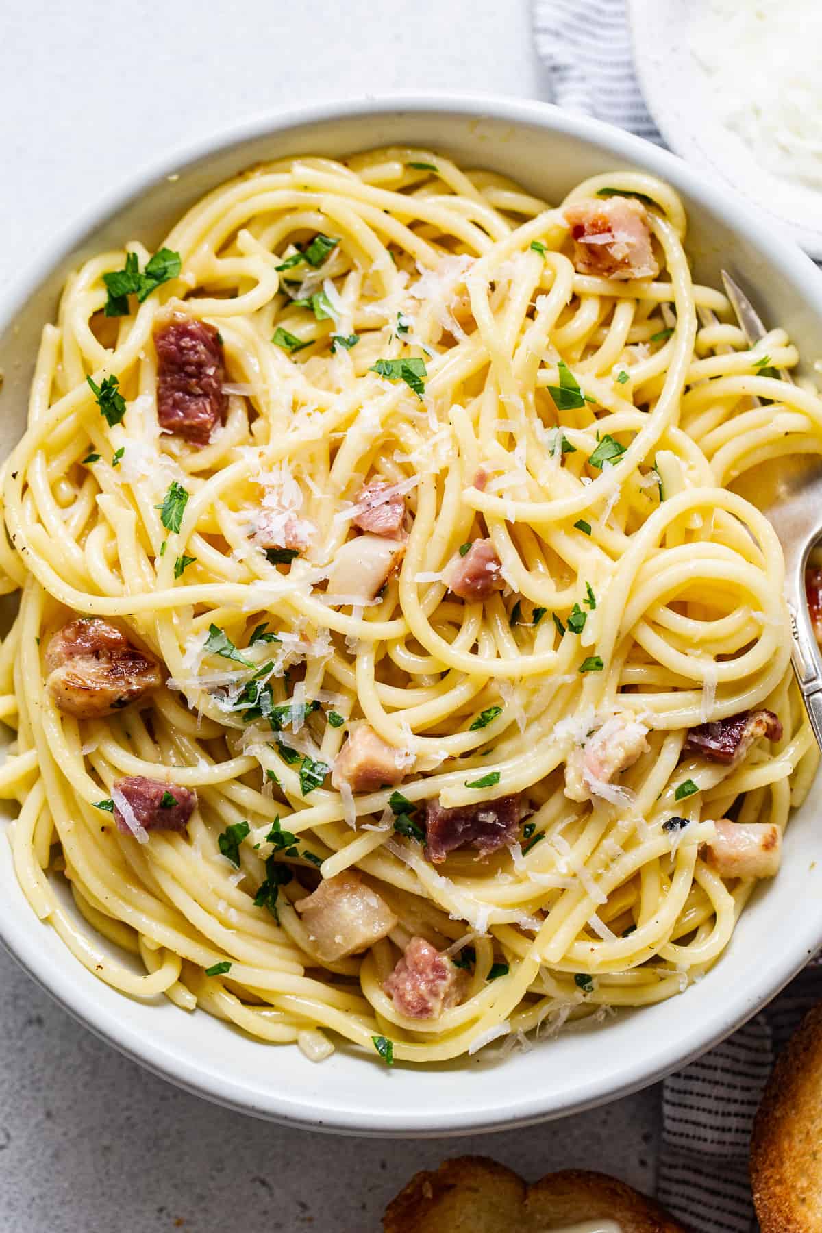 Pasta with bacon and parmesan in a white bowl.