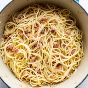 A pan full of spaghetti with bacon in it.