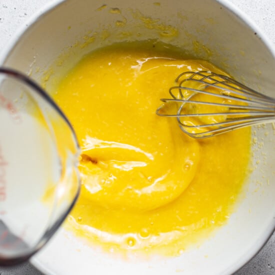 A bowl of yellow liquid with a whisk in it.