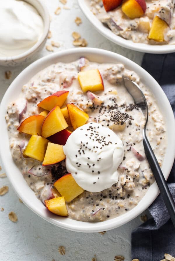 A bowl of oatmeal with peaches and yoghurt.