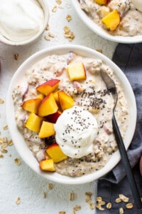 A bowl of oatmeal with peaches and yoghurt.