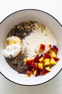 A bowl with yogurt, peaches and chia seeds.