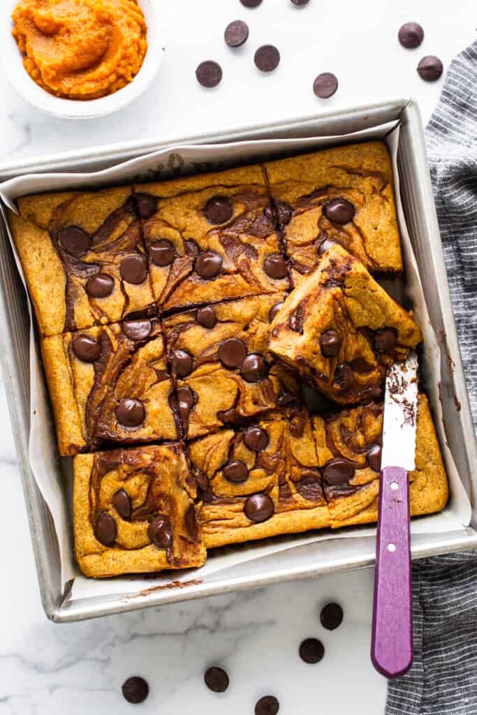 Pumpkin chocolate chip bars in a baking pan with a knife.