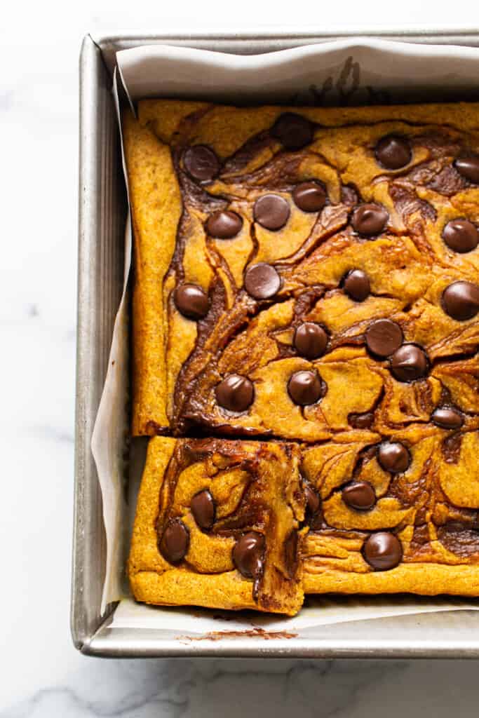 Pumpkin cheesecake bars in a baking pan with c،colate chips.