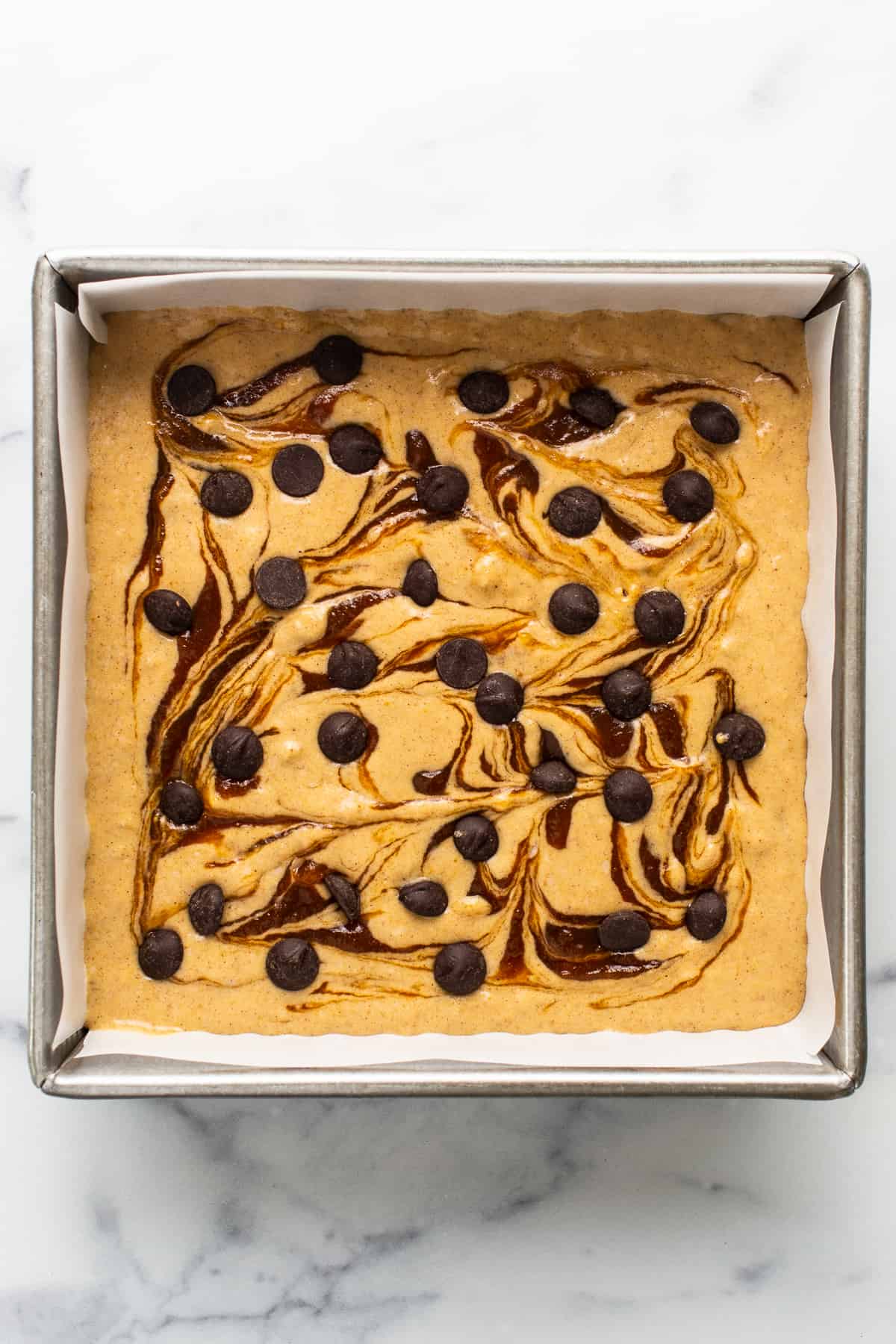 A brownie with chocolate chips and caramel sauce in a baking pan.