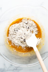 A bowl filled with flour and a wooden spatula.