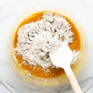 A bowl filled with flour and a wooden spatula.