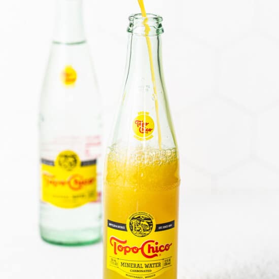 A bottle of orange juice being poured into a glass.