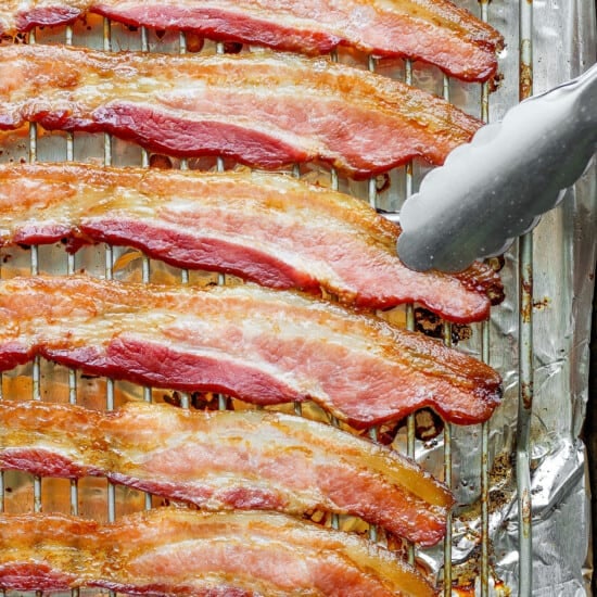 bacon on a baking sheet with a fork.