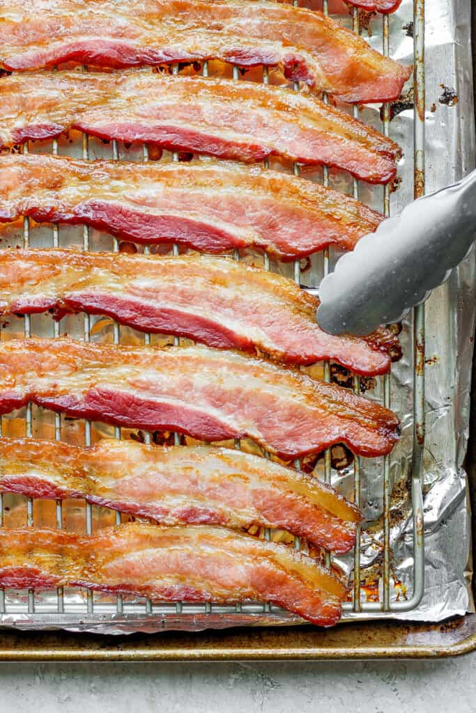 bacon on a baking sheet with a fork.