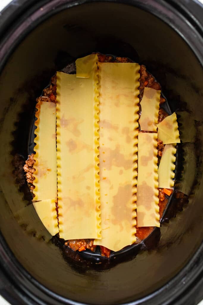 a crock ، filled with pasta and sauce.