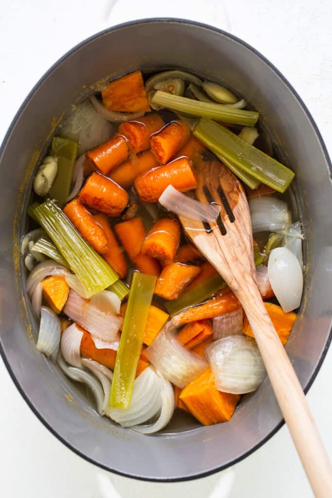 a pot filled with carrots, celery and onions.