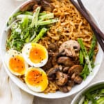 a bowl of asian noodle soup with an egg and mushrooms.