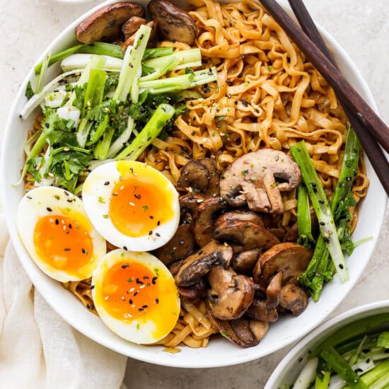 a bowl of asian noodle soup with an egg and mushrooms.