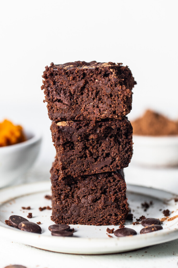 a stack of brownies sitting on top of a white plate.