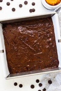 a pan of chocolate cake next to a bowl of chocolate chips.