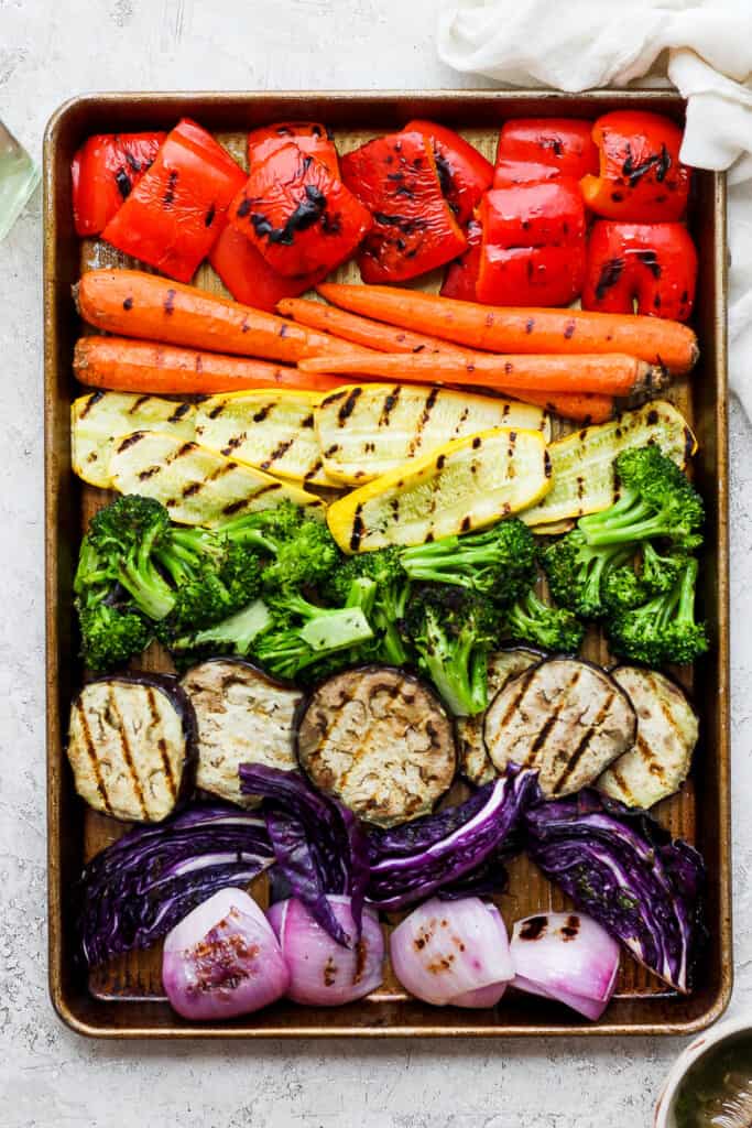 a tray of grilled vegetables including carrots, broccoli, red onions.