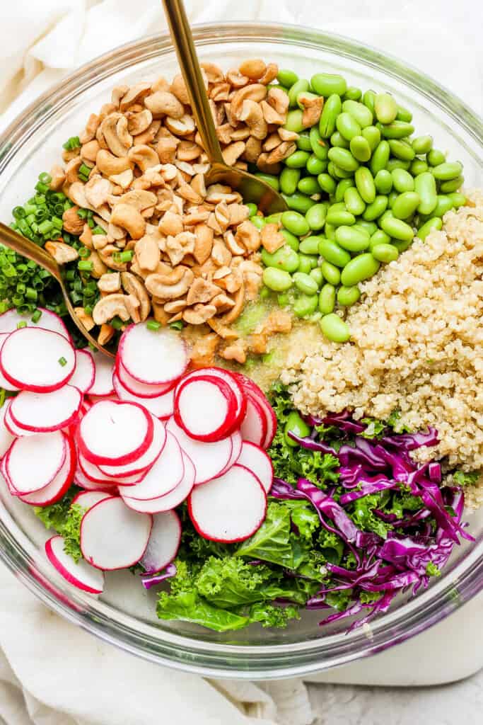 a bowl filled with greens, radishes, and quinoa.