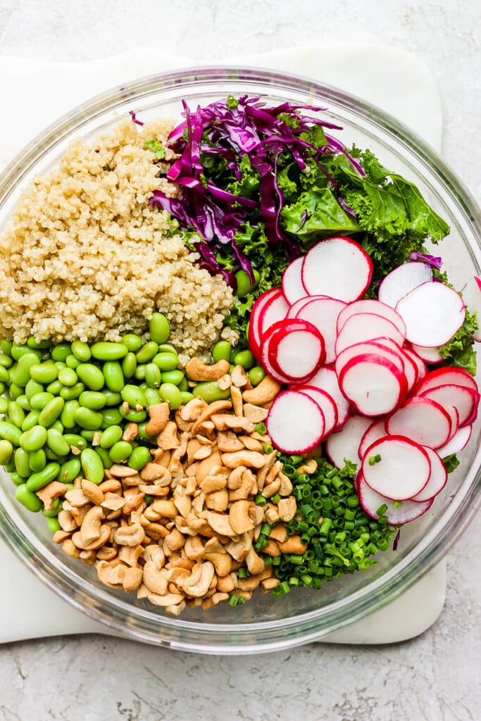 a bowl filled with greens, radishes and quinoa.