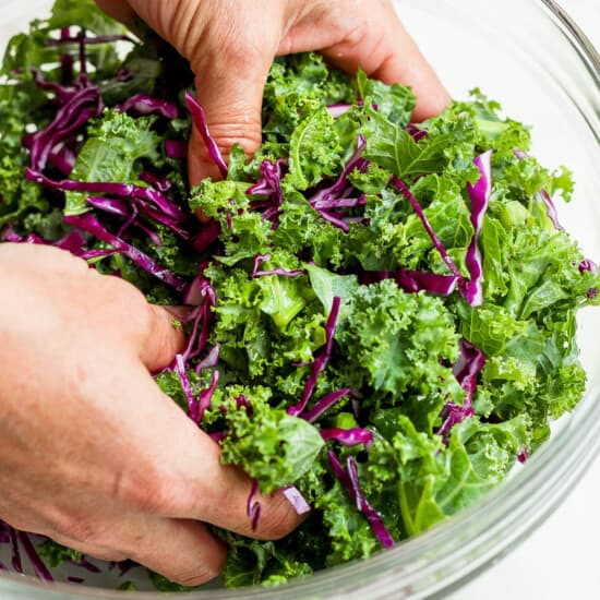 a person putting kale into a bowl.