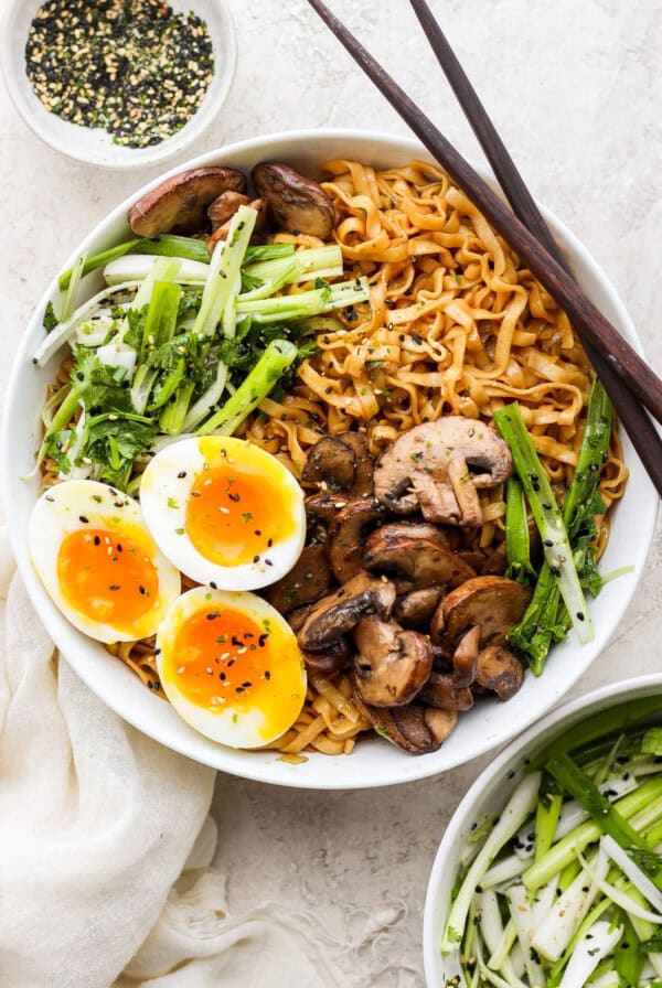 a bowl of asian noodles with an egg and mushrooms.