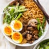 a bowl of asian noodles with an egg and mushrooms.