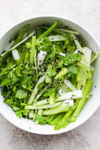 a bowl of greens with sesame seeds and sesame seeds.