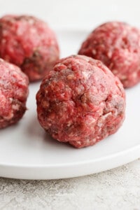 four meatballs on a white plate.