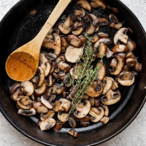 mushrooms in a skillet with a wooden spoon.