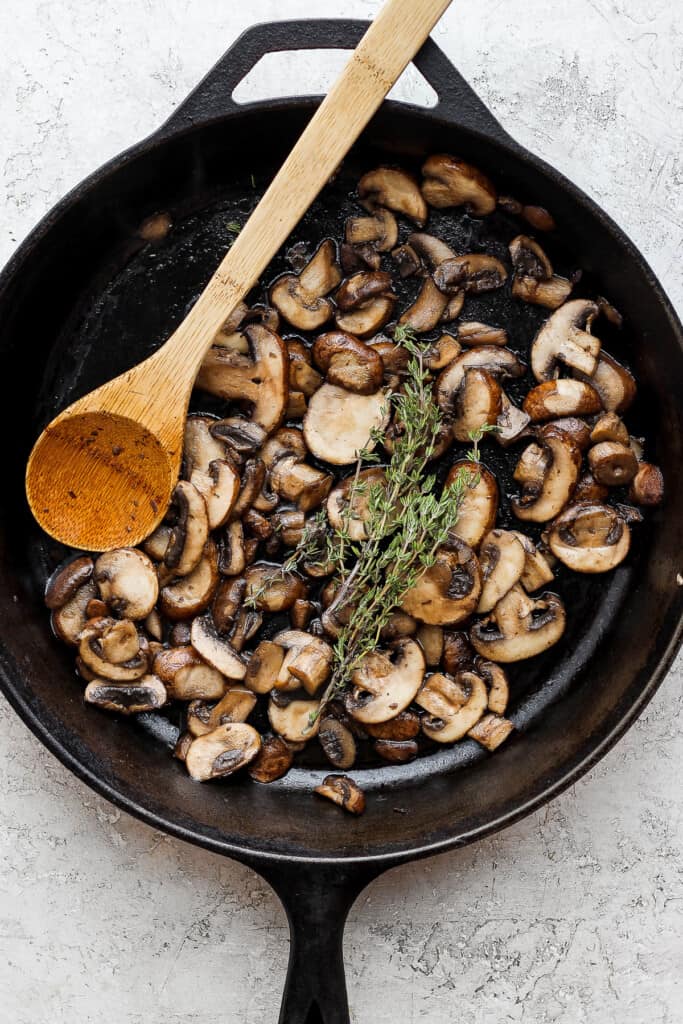 mushrooms in a skillet with a wooden spoon.