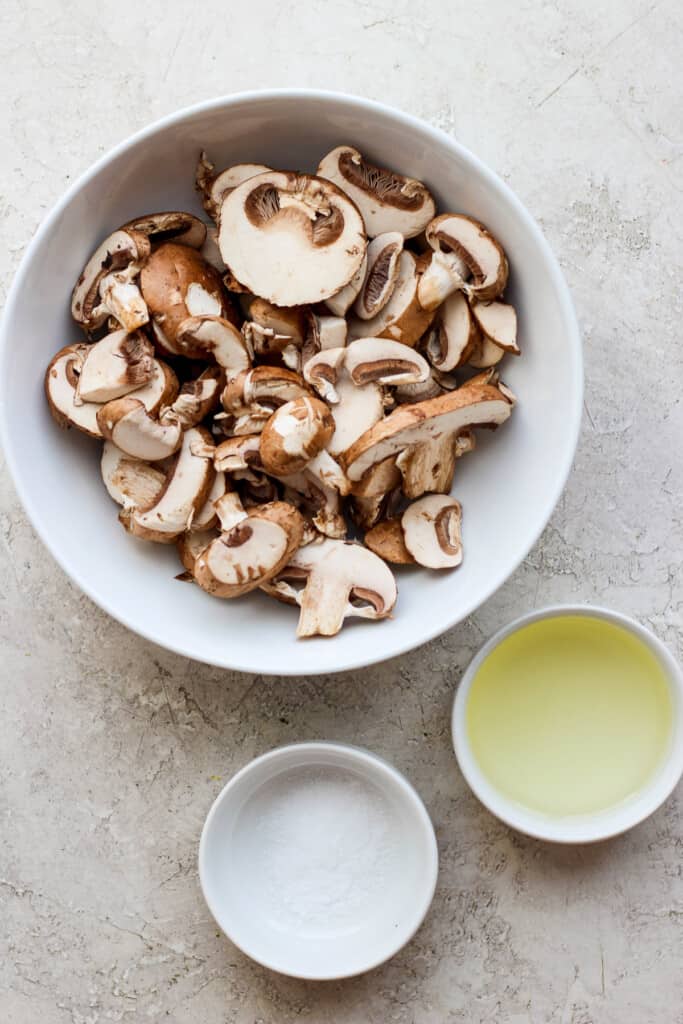 mushrooms in a bowl next to a bowl of oil.