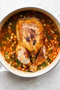 a chicken in a pot of soup.