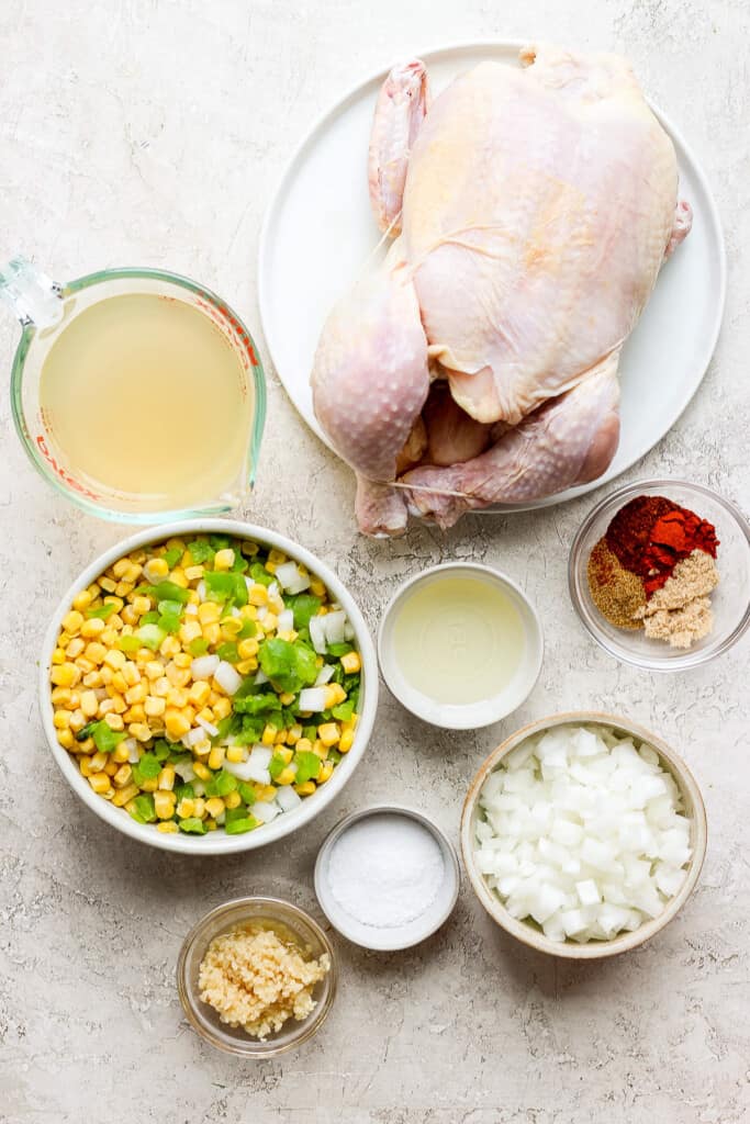 a chicken, corn, onions and other ingredients on a table.
