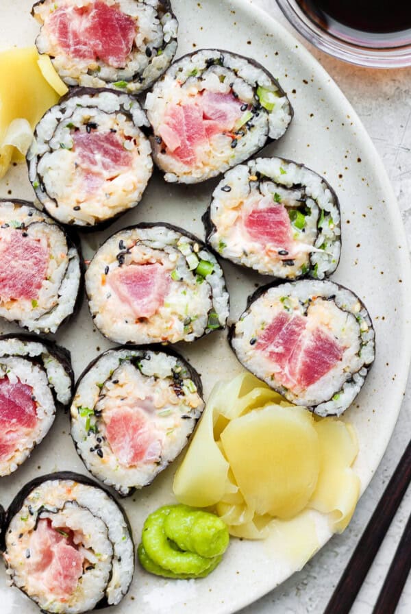 a plate of sushi with tuna and cucumber on it.