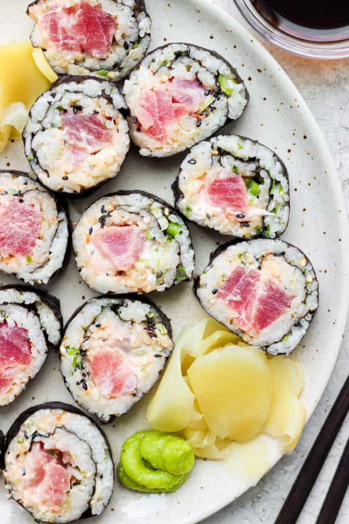 a plate of sushi with tuna and cucumber on it.