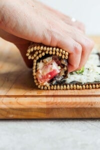 a person making a sandwich on a wooden cutting board.