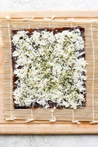 a pizza with cheese and herbs on a wooden cutting board.