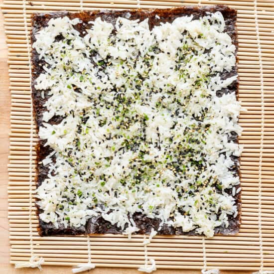 a pizza with cheese and herbs on a wooden cutting board.