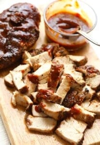 a bbq chicken dish served on a wooden cutting board.