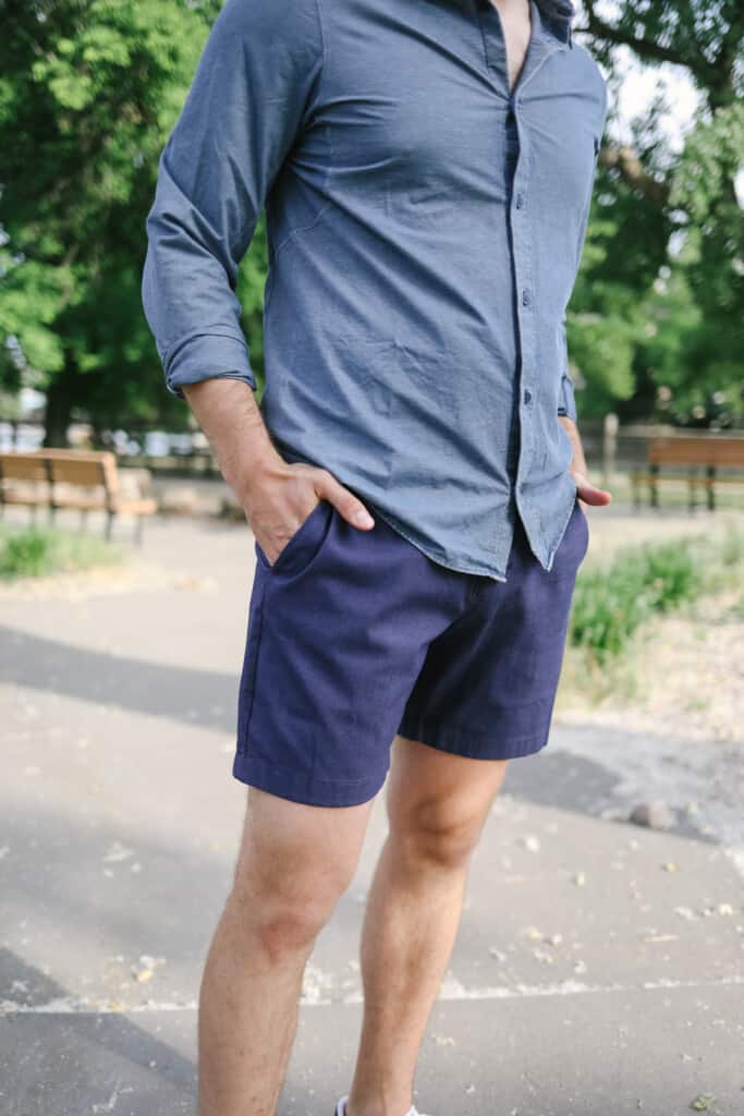 a man in a blue shirt and shorts posing for a picture.