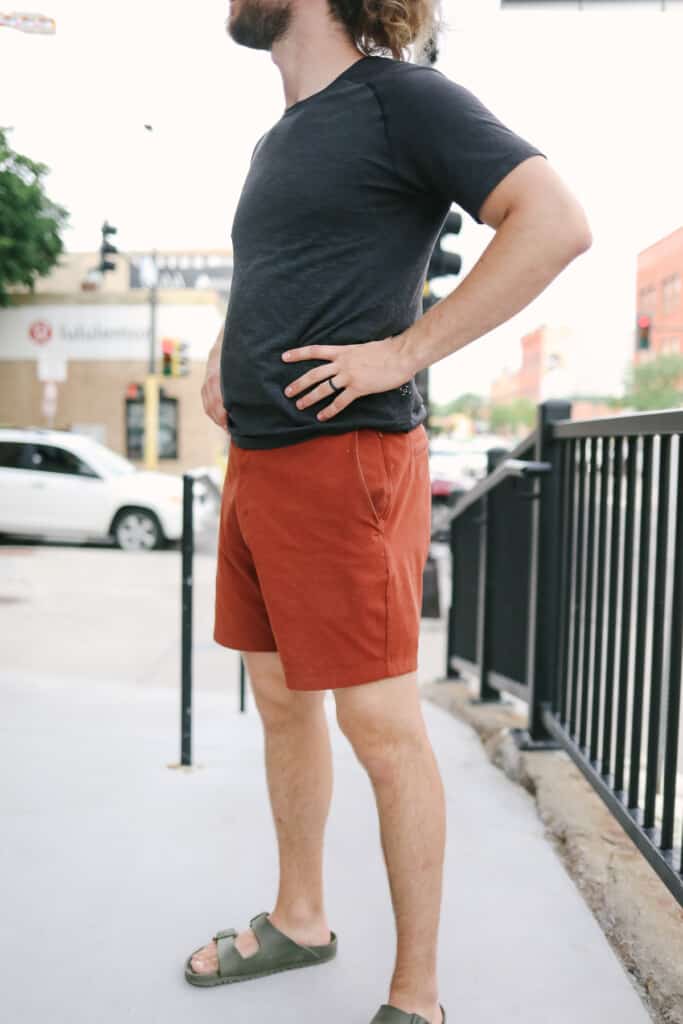 A man stands on a sidewalk with his hands on his hips.