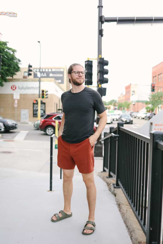A man stands on a sidewalk next to a traffic light.
