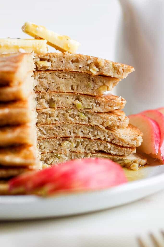 a stack of pancakes on a plate with apple slices.
