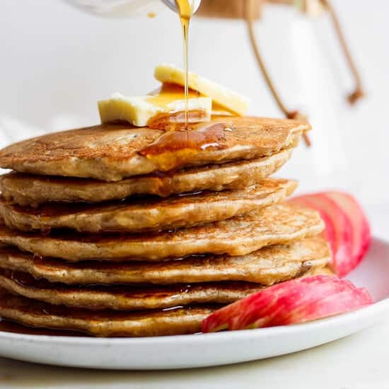 a stack of pancakes with syrup being poured onto them.