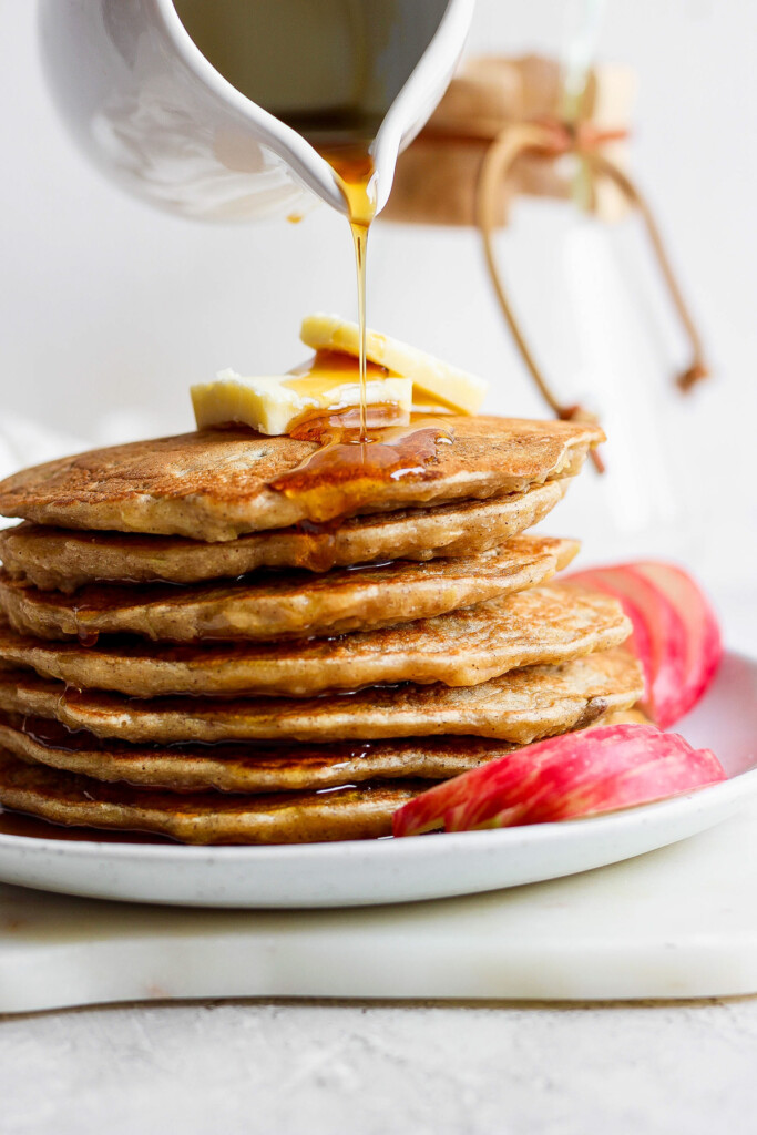 a stack of pancakes with syrup being poured onto them.